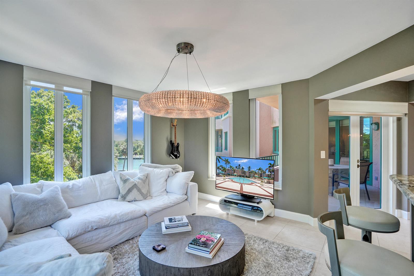A living room features a white sectional sofa, round coffee table, and large crystal chandelier — 100 SE 5th Avenue # 406, Boca Raton FL 33432, BOCA RATON, FL