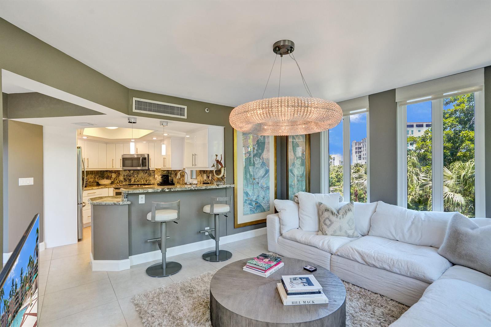 A living room with a white sectional sofa, round coffee table, and adjacent kitchen bar — 100 SE 5th Avenue # 406, Boca Raton FL 33432, BOCA RATON, FL