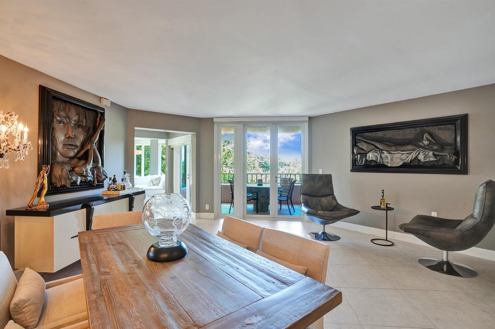 A dining room features a wooden table, two leather swivel chairs, and large wall art — 100 SE 5th Avenue # 406, Boca Raton FL 33432, BOCA RATON, FL