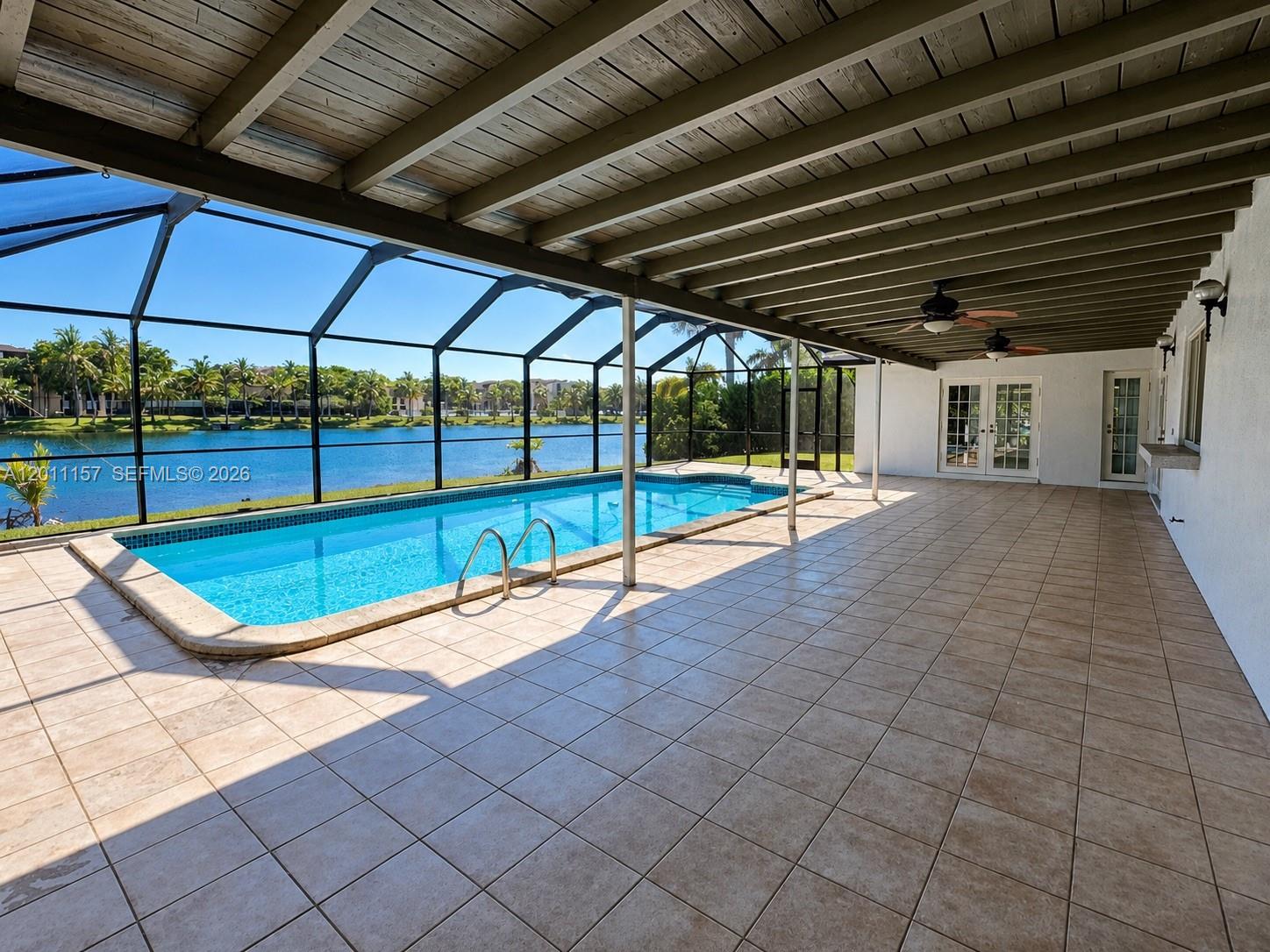 A screened-in patio features a rectangular swimming pool, tiled flooring, and a wooden ceiling — 14250 SW 85th St, Miami FL 33183, MIAMI, FL