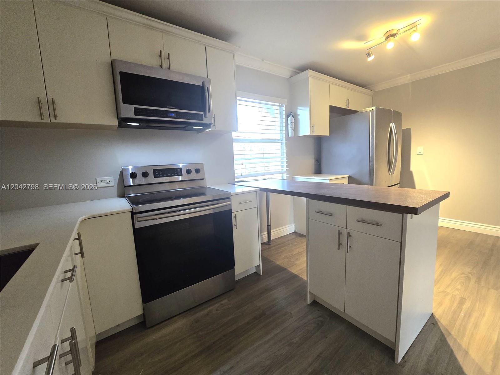 A kitchen features white cabinets, stainless steel appliances, a breakfast bar, and wood-look flooring — 914 SW 8th Avenue # 57, Gainesville FL 32601, GAINESVILLE, FL
