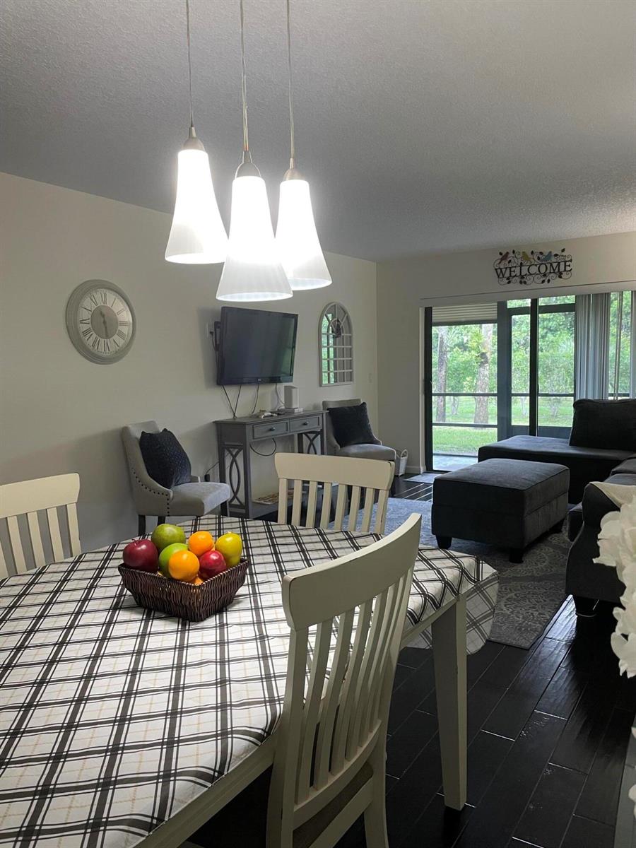 A dining area with a plaid tablecloth and pendant lights opens to a living room — 7879 Willow Spring Circle # 913, Lake Worth FL 33467, LAKE WORTH, FL