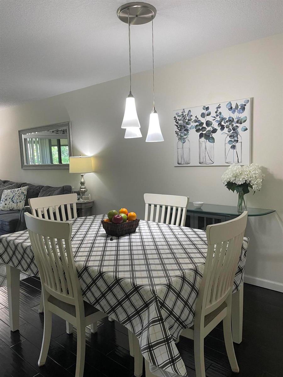A dining room features a plaid tablecloth, white chairs, pendant lighting, and wall art — 7879 Willow Spring Circle # 913, Lake Worth FL 33467, LAKE WORTH, FL