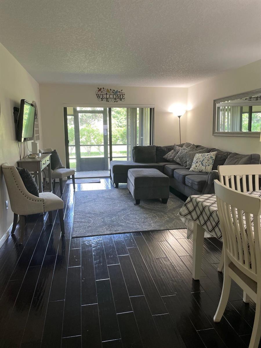 A living room features dark hardwood floors, a gray sectional sofa, and a sliding glass door — 7879 Willow Spring Circle # 913, Lake Worth FL 33467, LAKE WORTH, FL