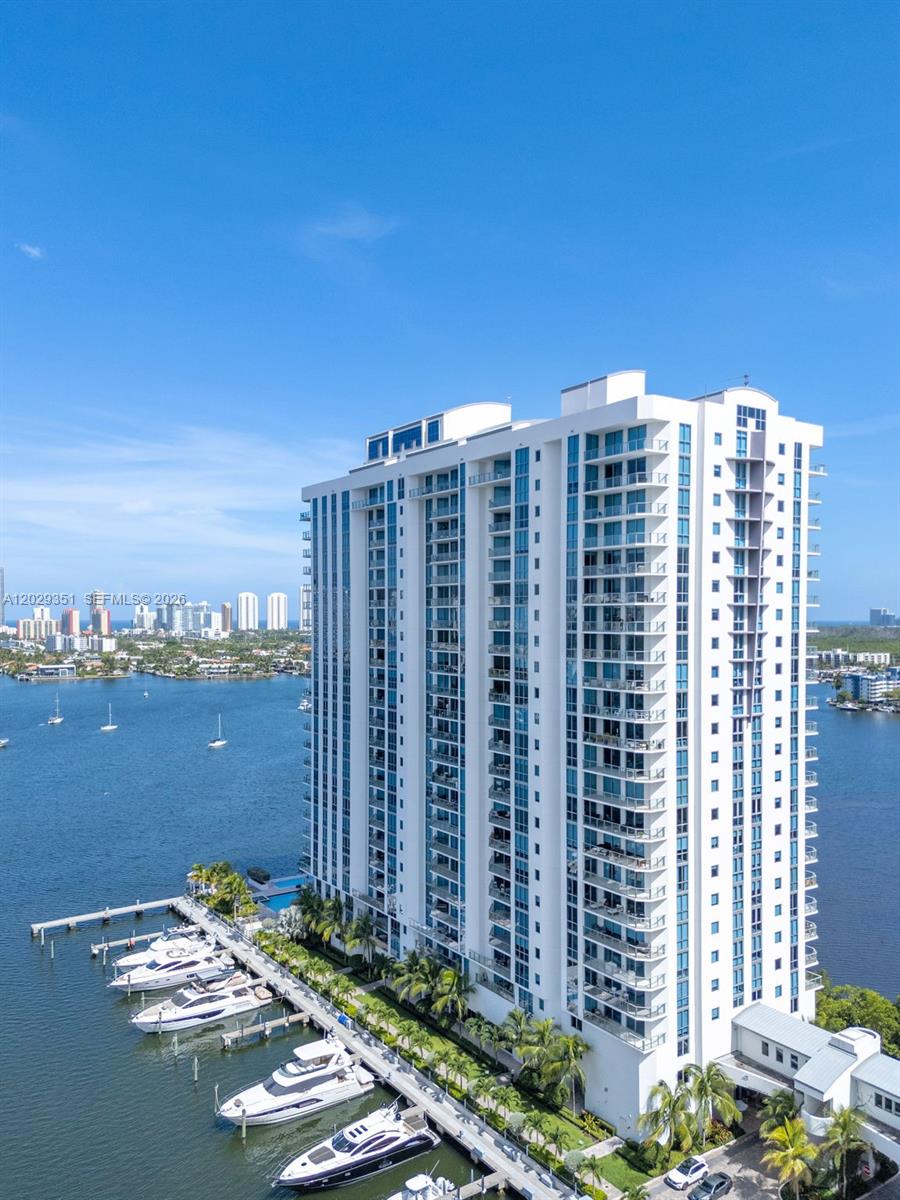 An aerial view shows a tall residential building next to a marina with docked yachts — 17111 BISCAYNE BL # 506, North Miami Beach FL 33160, NORTH MIAMI BEACH, FL