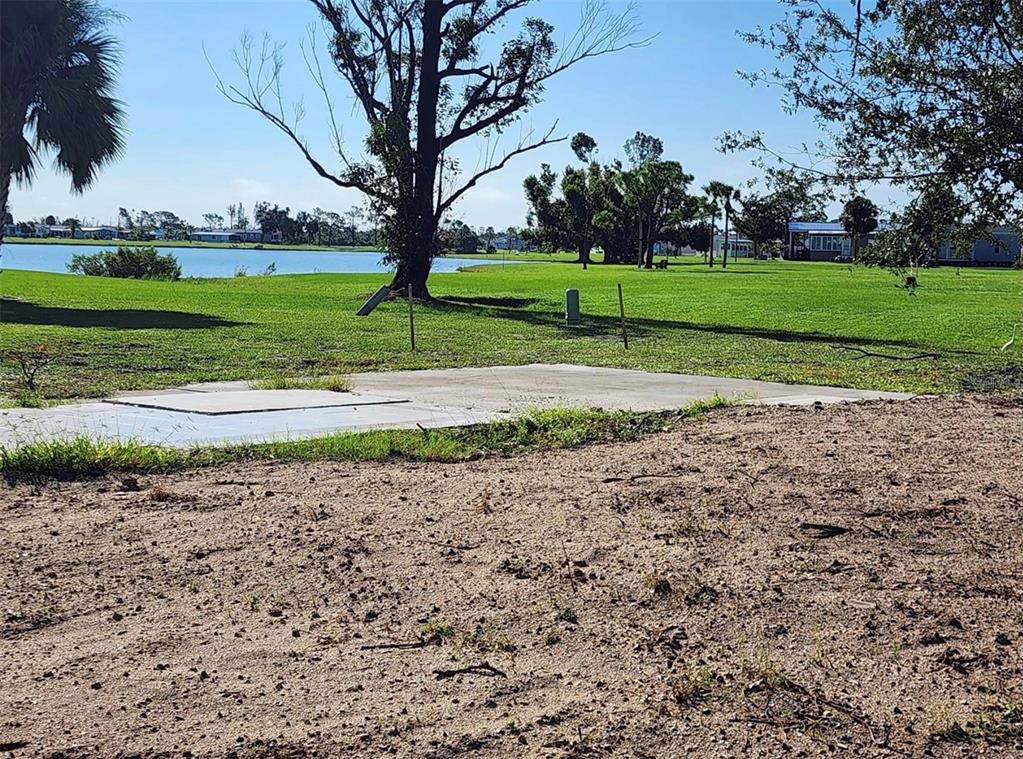 A concrete slab sits on a grassy lot overlooking a lake with trees nearby — 7368 VARLEY CIRCLE, PORT CHARLOTTE, FL