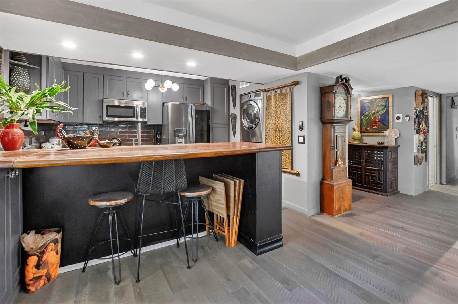 A kitchen features a wooden breakfast bar, gray cabinets, and a tall grandfather clock — 6957 Rain Forest Drive, Boca Raton FL 33434, BOCA RATON, FL