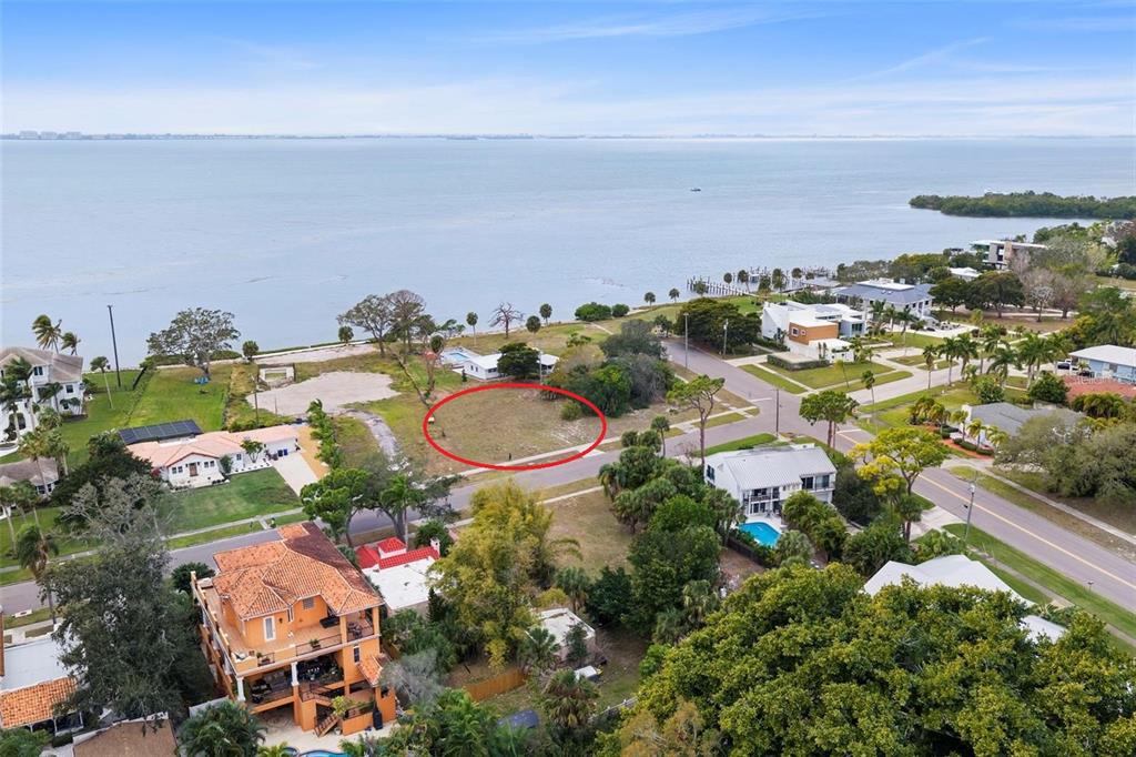 An aerial view shows a vacant waterfront lot circled in red near a residential street — 7510 WESTMORELAND DRIVE, SARASOTA, FL