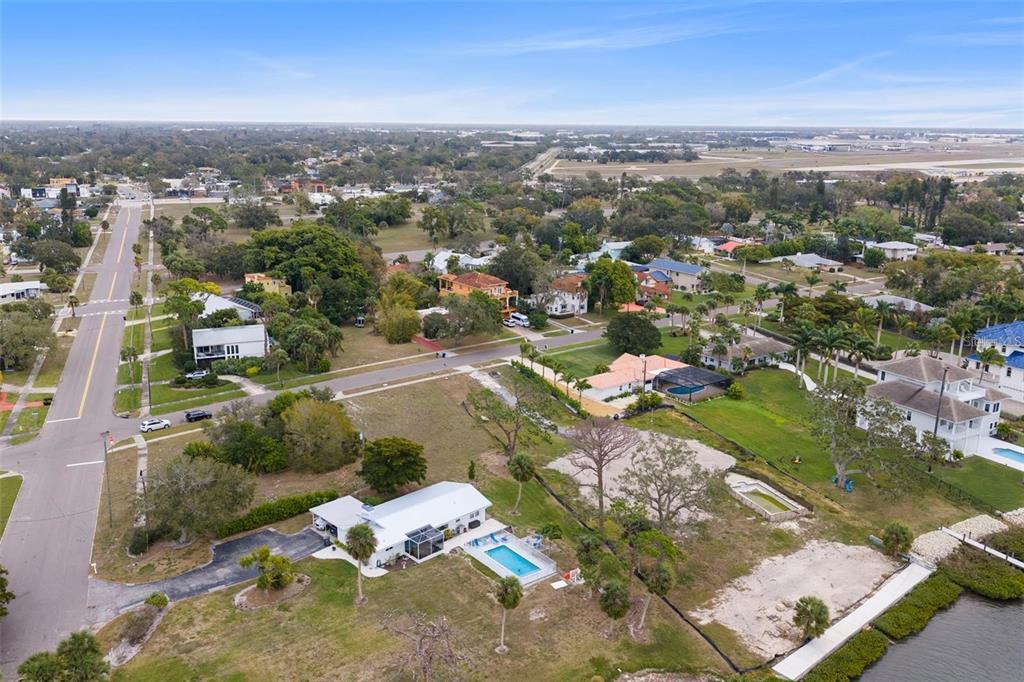 An aerial view shows a waterfront house with a pool and a large vacant lot — 7510 WESTMORELAND DRIVE, SARASOTA, FL
