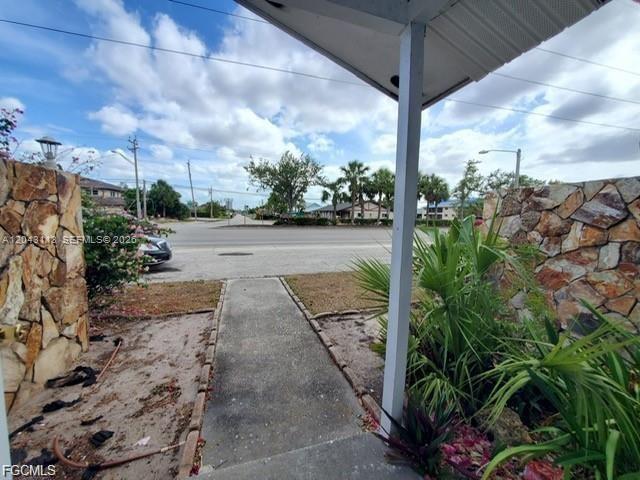 A concrete walkway leads from a covered porch toward a street lined with palm trees — 257 CAPE CORAL PKY E # B, Cape Coral FL 33904, CAPE CORAL, FL