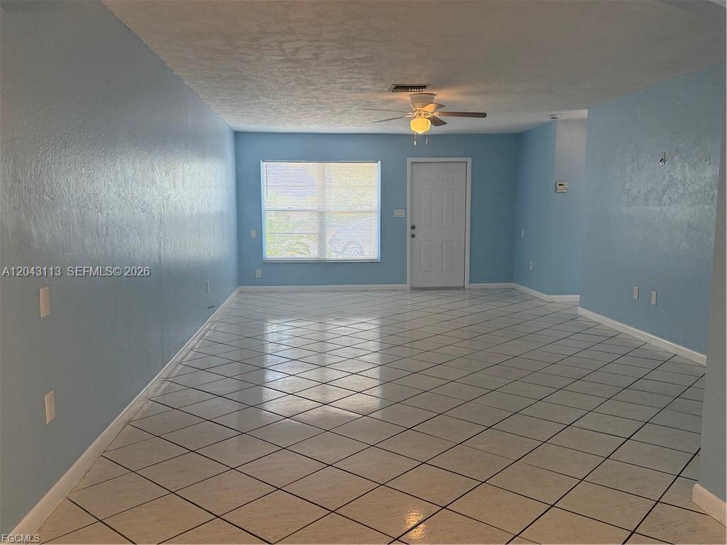 An empty room features light blue walls, a ceiling fan, and white diagonal-patterned floor tiles — 257 CAPE CORAL PKY E # B, Cape Coral FL 33904, CAPE CORAL, FL