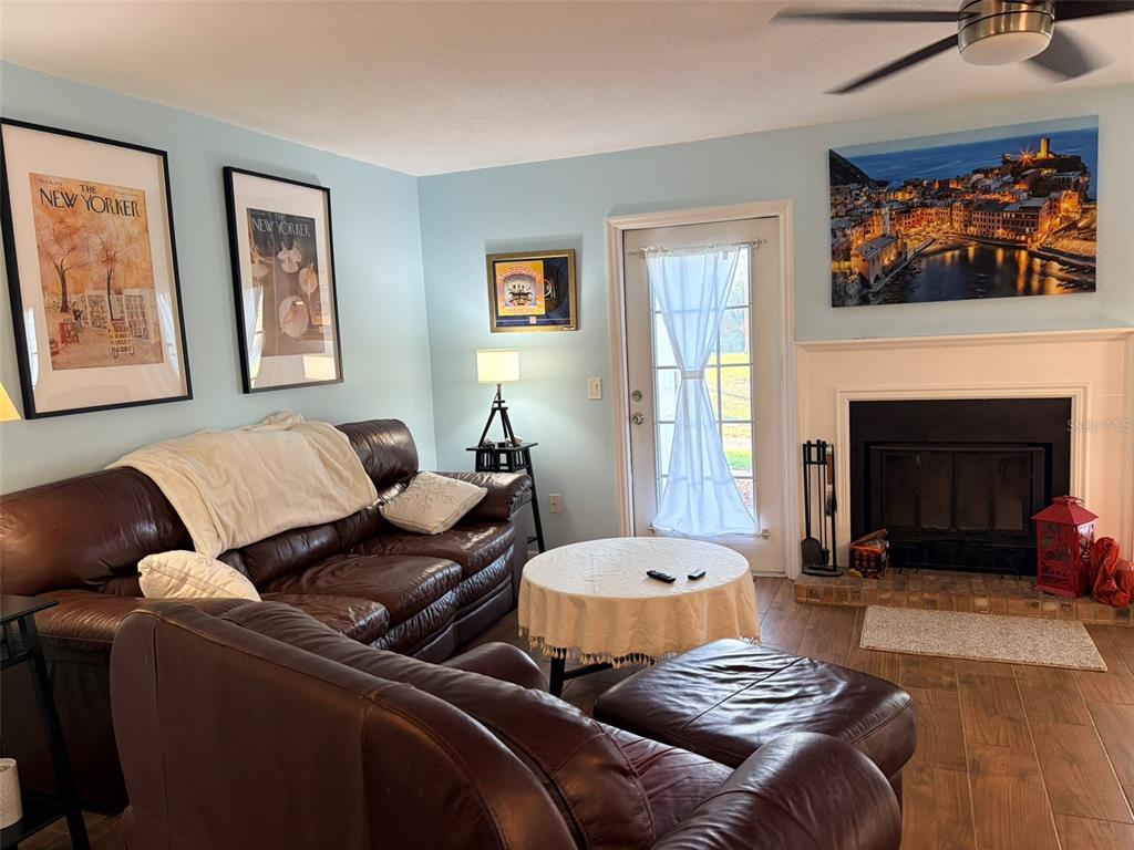 A living room and dining area with light blue walls, wood-look tile, and white cabinetry — 16302 RAMBLING VINE DRIVE W, TAMPA, FL