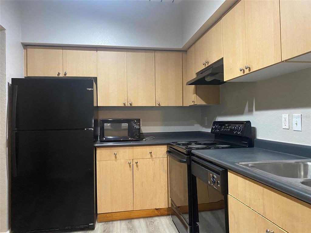 A kitchen features light wood cabinets, black appliances, and dark countertops — 520 S ARMENIA AVENUE UNIT 1228, TAMPA, FL