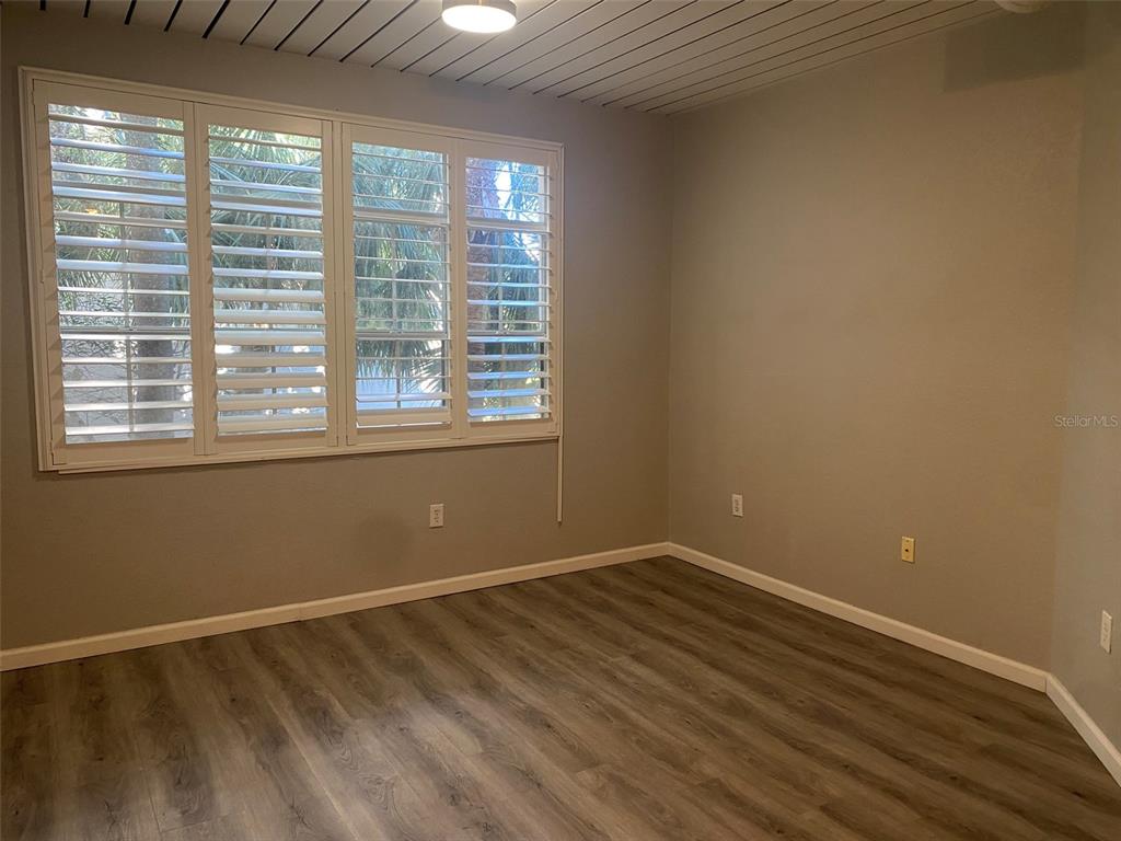 An empty room features gray walls, wood-look flooring, a slatted ceiling, and white plantation shutters — 520 S ARMENIA AVENUE UNIT 1228, TAMPA, FL