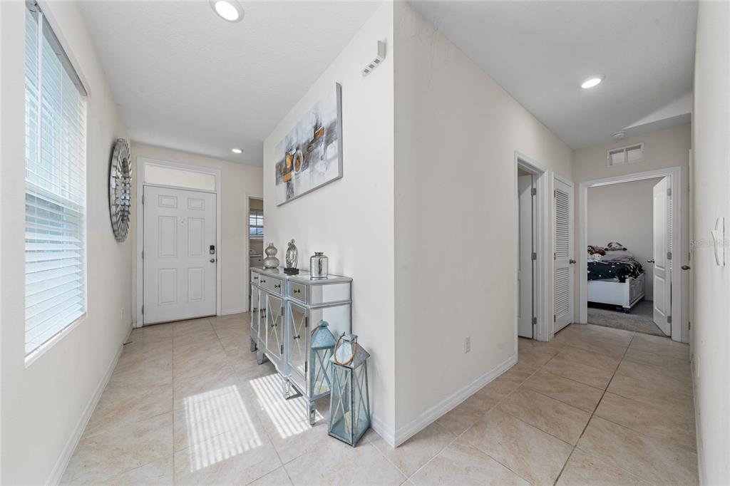 A bright entryway features tiled floors, a mirrored console table, and a view into a bedroom — 1107 CASCADE DRIVE, DAVENPORT, FL
