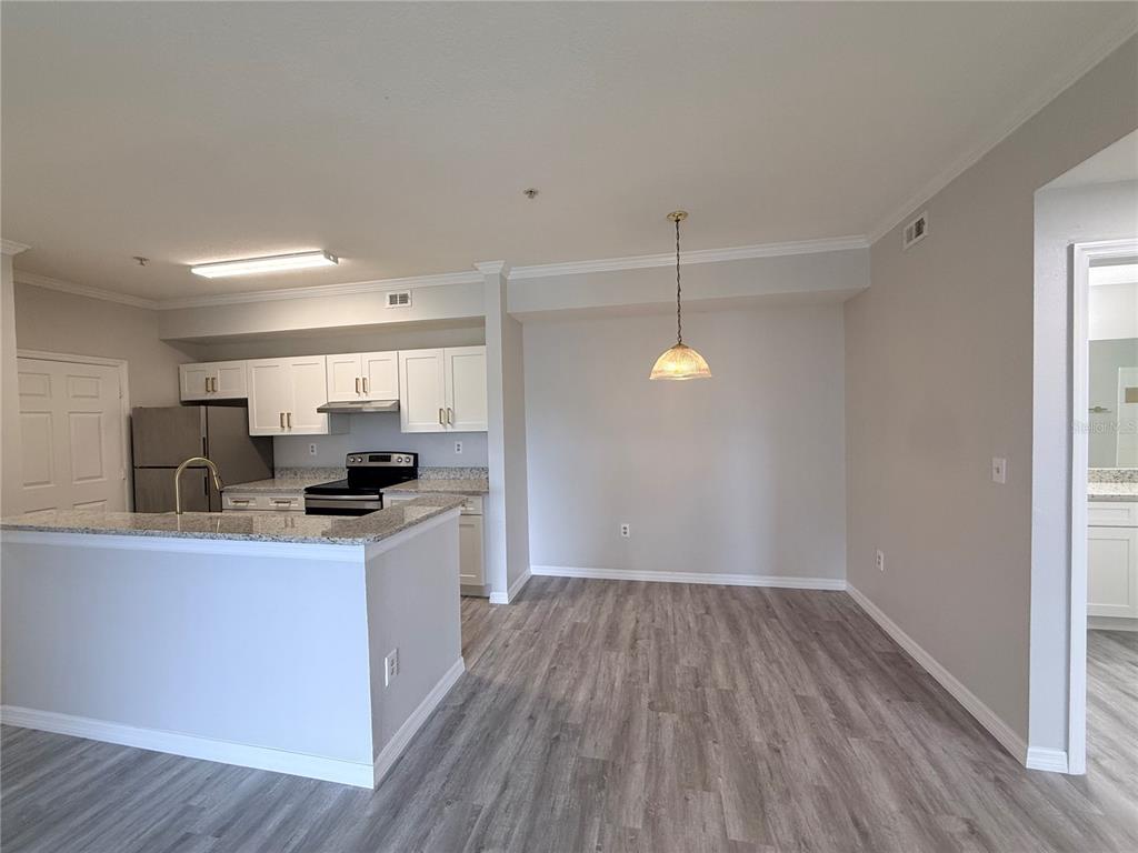 An open-concept kitchen and dining area featuring white cabinets, granite countertops, and wood-look flooring — 5618 PINNACLE HEIGHTS CIRCLE UNIT 305, TAMPA, FL