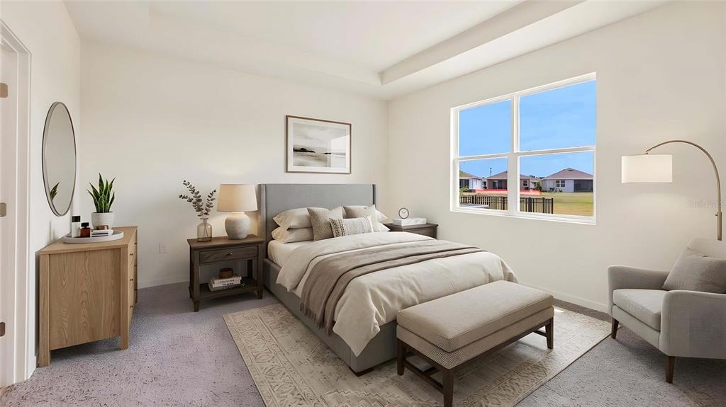 A bedroom features a gray upholstered bed, a wooden dresser, and an armchair by a window — 4550 NW 39TH STREET ROAD, OCALA, FL
