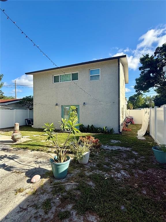 The exterior of a two-story stucco house features a backyard with potted plants and fencing — 2623 14TH AVENUE N, ST PETERSBURG, FL