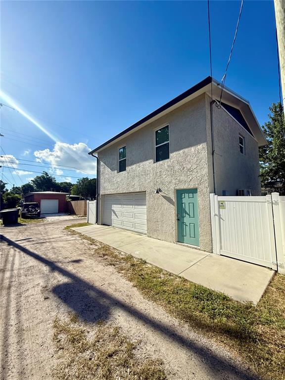 A two-story building with a garage, a teal door, and a white vinyl fence — 2623 14TH AVENUE N, ST PETERSBURG, FL