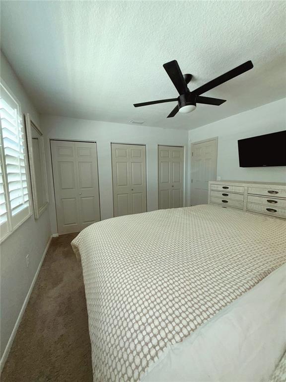 A bedroom features a ceiling fan, carpeted flooring, three closet doors, and a white dresser — 2623 14TH AVENUE N, ST PETERSBURG, FL