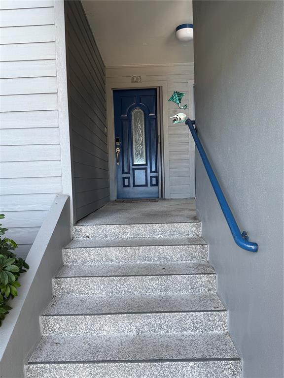 A set of concrete stairs leads up to a blue front door numbered 103 — 910 PINELLAS BAYWAY S UNIT 103, TIERRA VERDE, FL