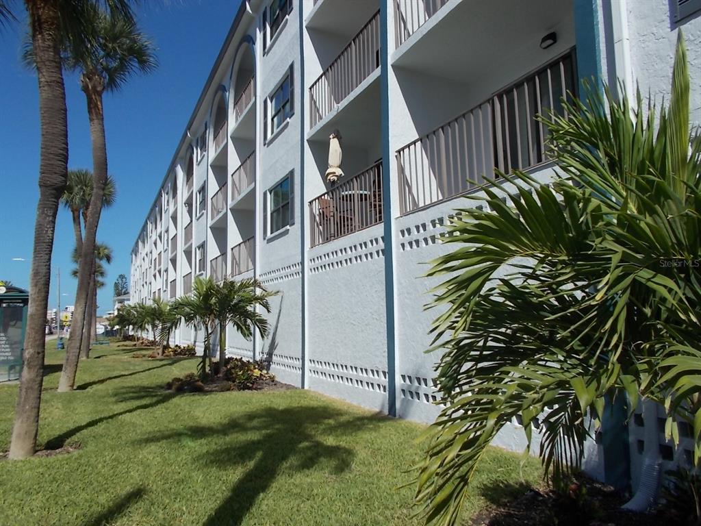 A multi-story apartment building with balconies and palm trees on a sunny day — 14001 GULF BOULEVARD UNIT 407, MADEIRA BEACH, FL
