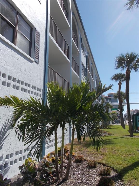 A low-angle view of a multi-story apartment building exterior with balconies and palm trees — 14001 GULF BOULEVARD UNIT 407, MADEIRA BEACH, FL