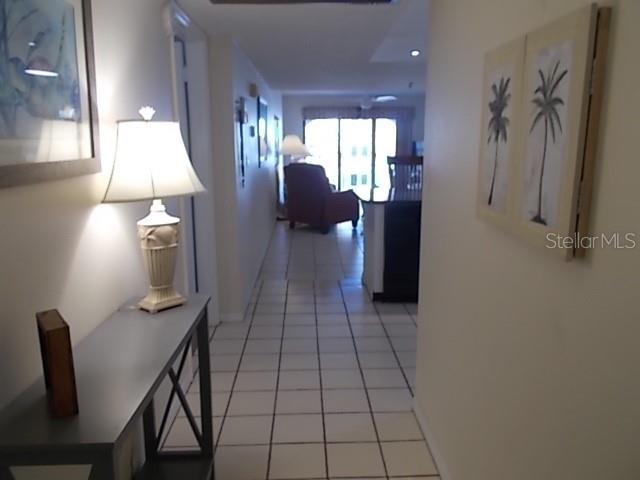A hallway with tiled floors leads from a console table toward a living area — 14001 GULF BOULEVARD UNIT 407, MADEIRA BEACH, FL
