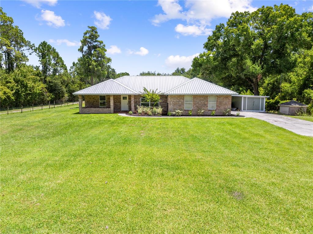A single-story brick house with a metal roof sits on a large, grassy lot — 3839 LAKEVIEW ACRES RD, ST CLOUD, FL