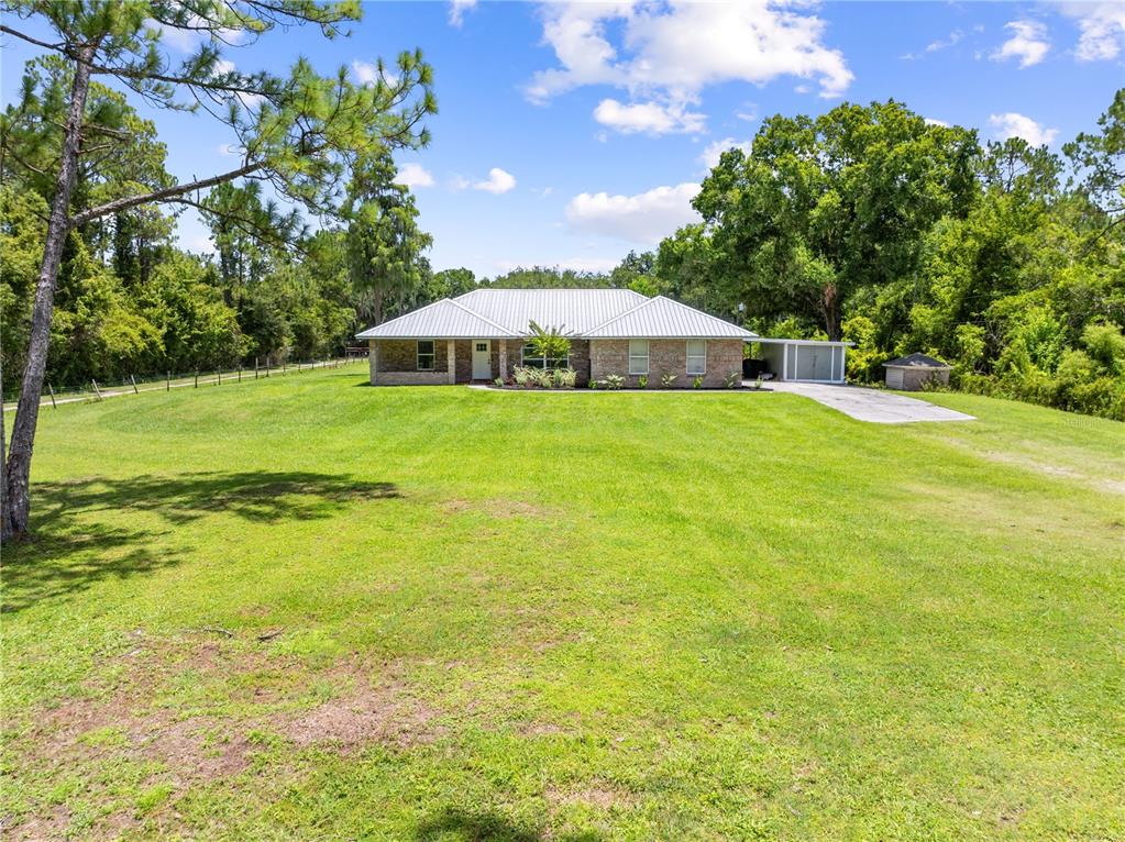 A single-story brick house with a metal roof sits on a large, grassy lot — 3839 LAKEVIEW ACRES RD, ST CLOUD, FL
