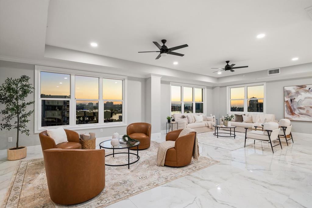 A spacious living room features white marble floors, two ceiling fans, and large windows — 211 DOLPHIN POINT UNIT 501, CLEARWATER, FL