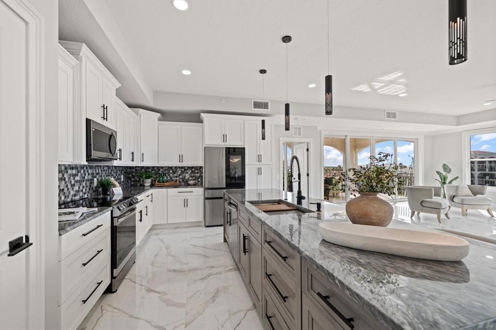 A modern kitchen features white upper cabinets, gray lower cabinets, and a marble-topped island — 211 DOLPHIN POINT UNIT 501, CLEARWATER, FL