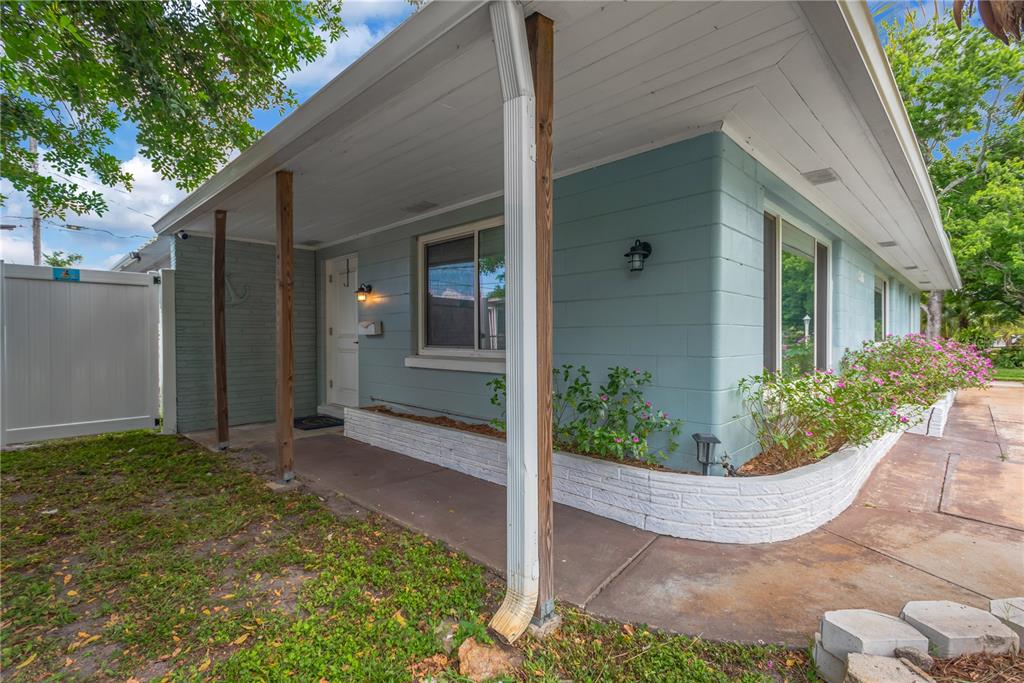 A light blue concrete block house features a covered porch with wooden support posts — 1306 30TH STREET W, BRADENTON, FL