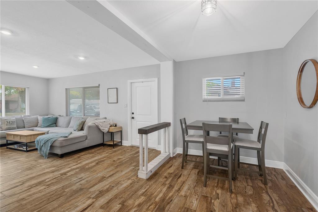 A living room and dining area with gray walls, wood-look flooring, and a sectional sofa — 1306 30TH STREET W, BRADENTON, FL