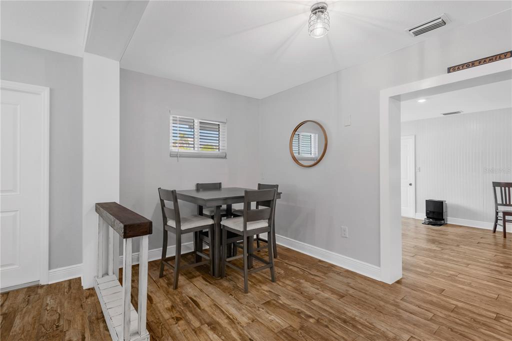 A dining area features a dark wood table with four chairs, light walls, and wood flooring — 1306 30TH STREET W, BRADENTON, FL