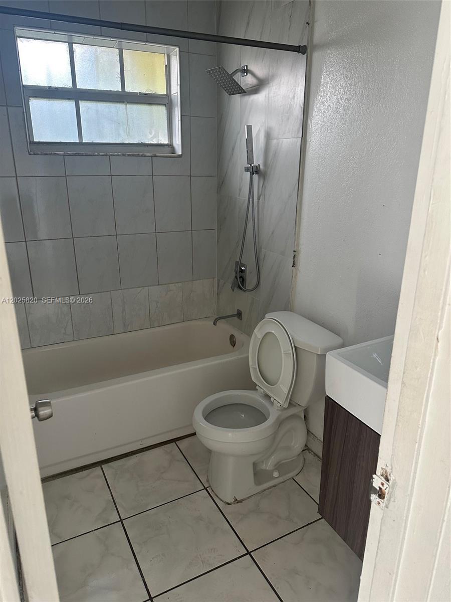 A small bathroom features a tiled bathtub, a toilet, and a vanity sink — 7024 NW 6th Ave # 1, Miami FL 33150, MIAMI, FL