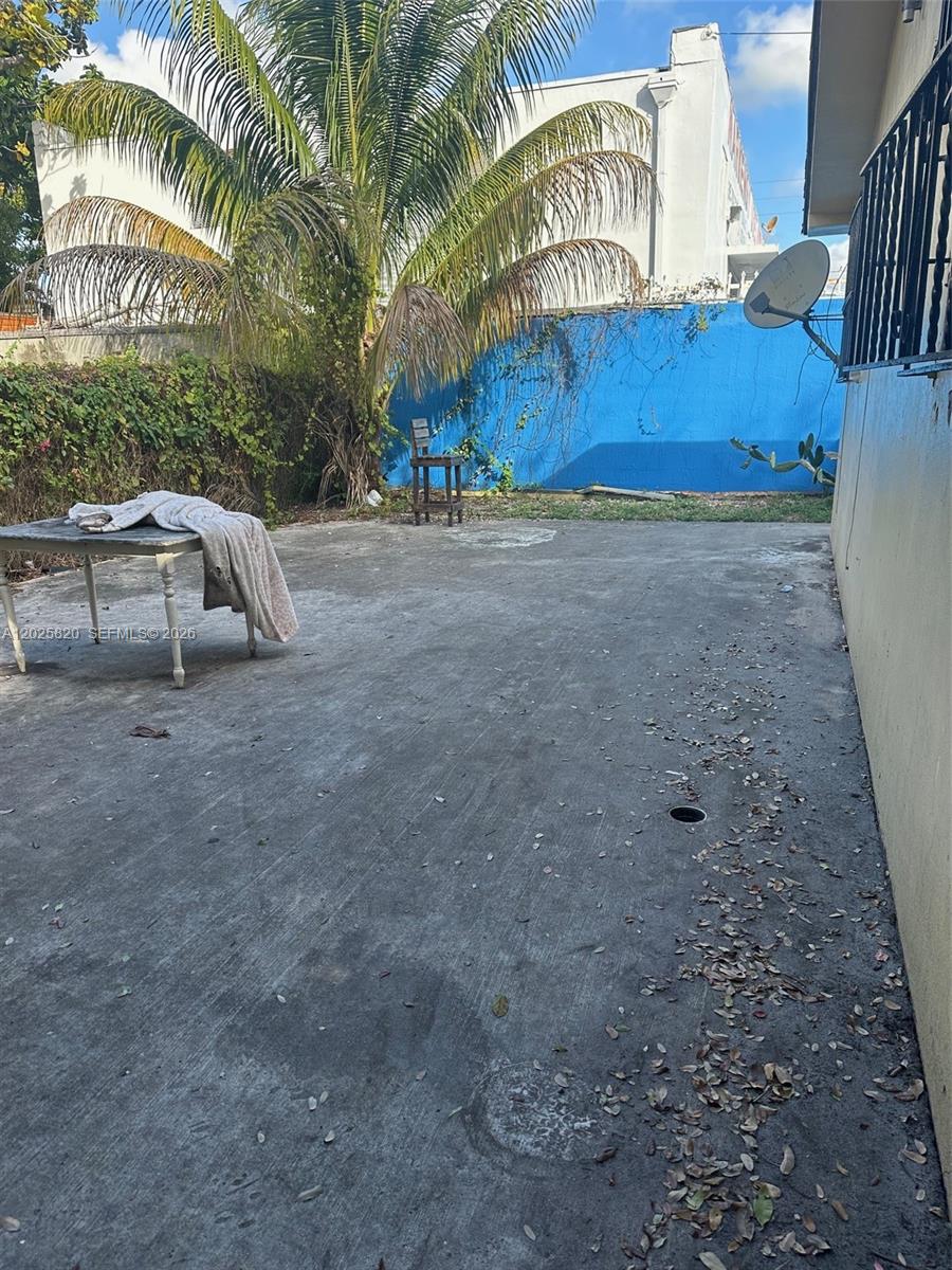 A concrete patio area features a table, a wooden chair, and a blue wall — 7024 NW 6th Ave # 1, Miami FL 33150, MIAMI, FL