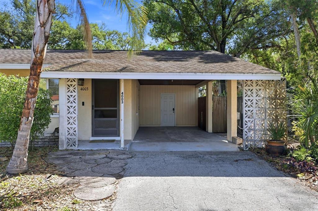 A single-story house with a yellow stucco exterior, a carport, and a decorative concrete pillar — 4003 BOOTH PLACE, SARASOTA, FL