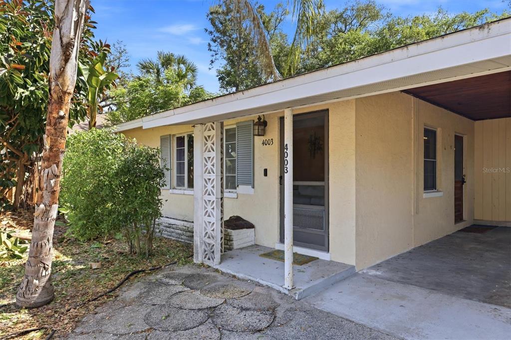 An aerial view shows an L-shaped house with a gray shingled roof surrounded by trees — 4003 BOOTH PLACE, SARASOTA, FL