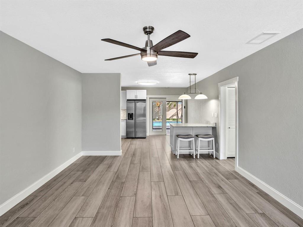 A dining area with wood-look flooring, a ceiling fan, and a breakfast bar with stools — 541 NE 18th Street, Boca Raton FL 33432, BOCA RATON, FL