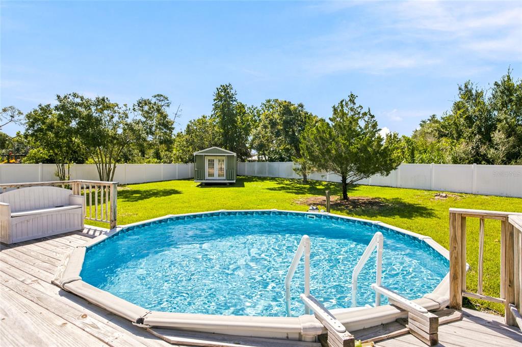 A backyard features an above-ground swimming pool with a wooden deck and a small storage shed — 10917 SW 45TH COURT, OCALA, FL