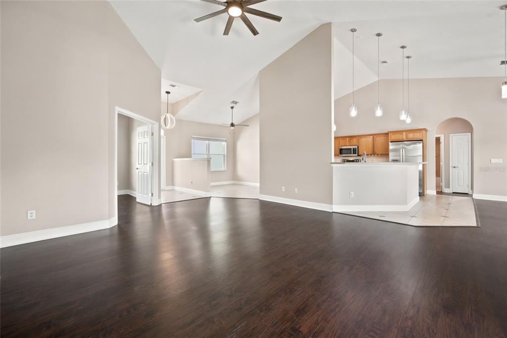 A spacious living area with dark wood floors, vaulted ceilings, and an open-concept kitchen — 10917 SW 45TH COURT, OCALA, FL