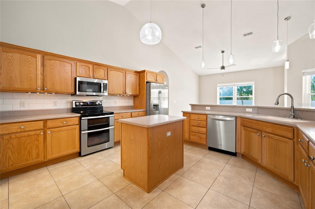 A kitchen with oak cabinets, stainless steel appliances, a center island, and tile flooring — 10917 SW 45TH COURT, OCALA, FL