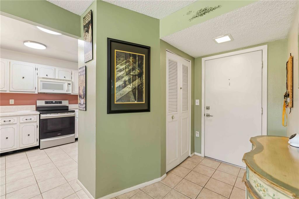 A view of an entryway with tile floors, a white door, and an adjacent kitchen — 3680 IRONWOOD CIRCLE UNIT 202L, BRADENTON, FL