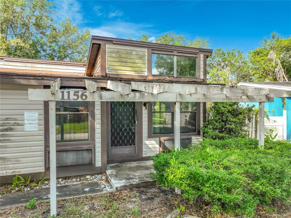 The exterior of a single-story house features a wooden pergola over the front entrance — 1156 ERROL PLACE CIRCLE, APOPKA, FL