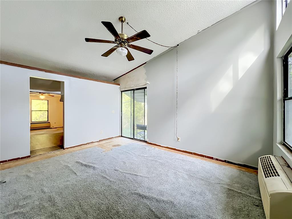 An empty room features a vaulted ceiling, a ceiling fan, gray carpet, and sliding glass doors — 1156 ERROL PLACE CIRCLE, APOPKA, FL