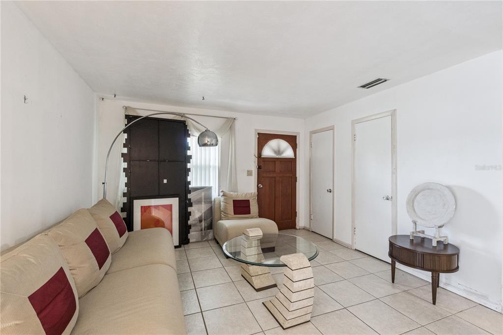 A living room with tiled floors, a beige sofa, a glass coffee table, and two doors — 3309 COLEMAN PLACE, ORLANDO, FL