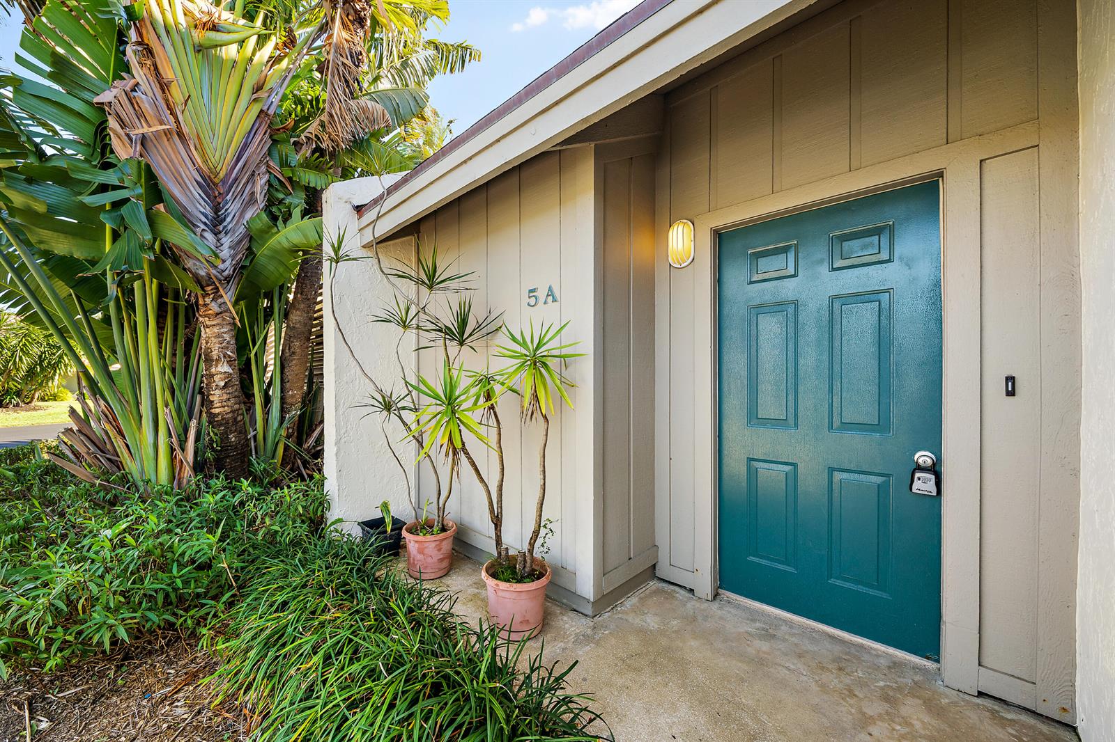 A teal front door with a lockbox sits beside two potted plants and a wall sign — 1605 S Us Highway 1 # 5a, Jupiter FL 33477, JUPITER, FL