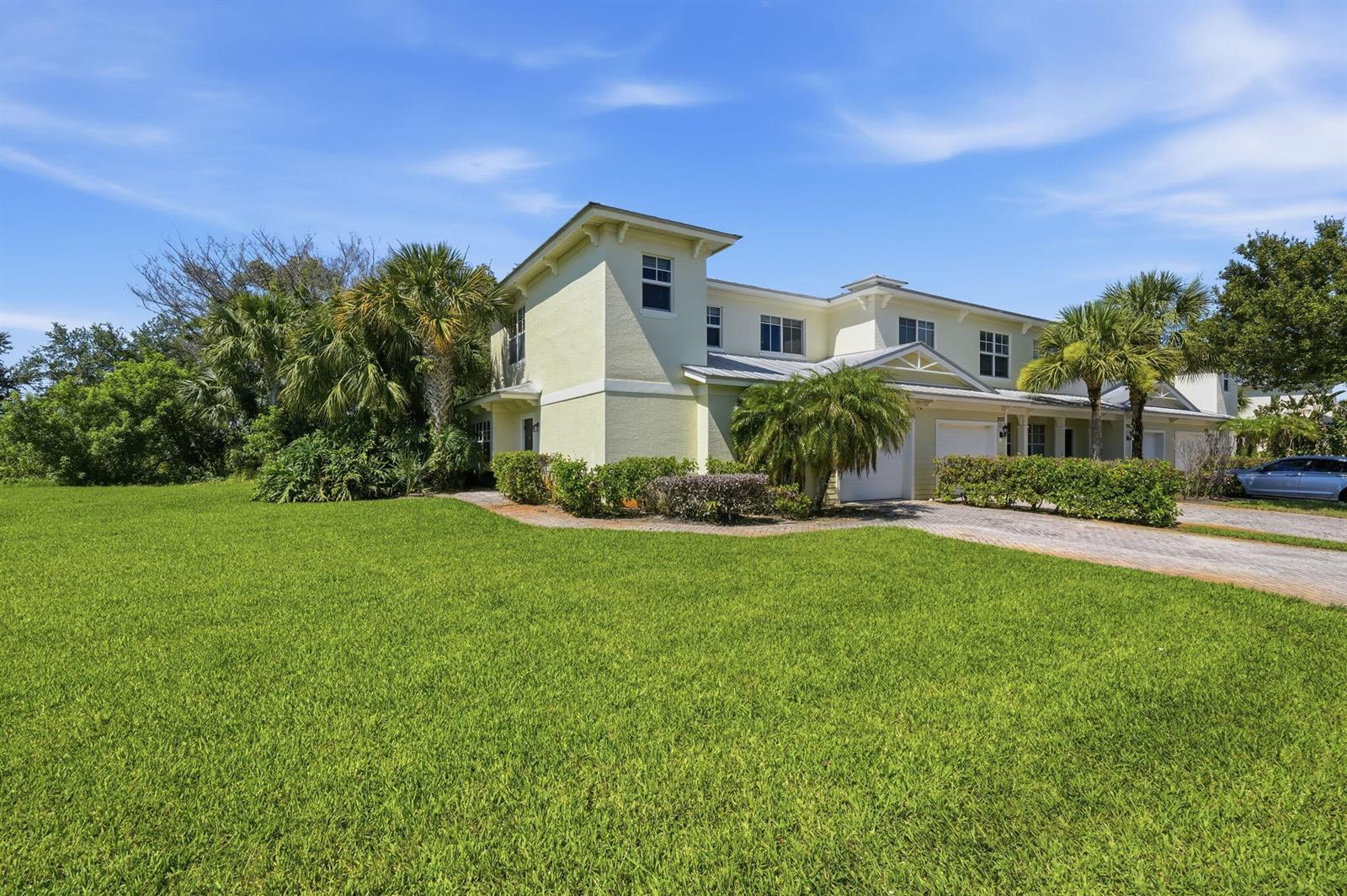 A two-story light yellow townhouse with a paved driveway, palm trees, and a grassy lawn — 2551 Creekside Drive, Fort Pierce FL 34981, FORT PIERCE, FL