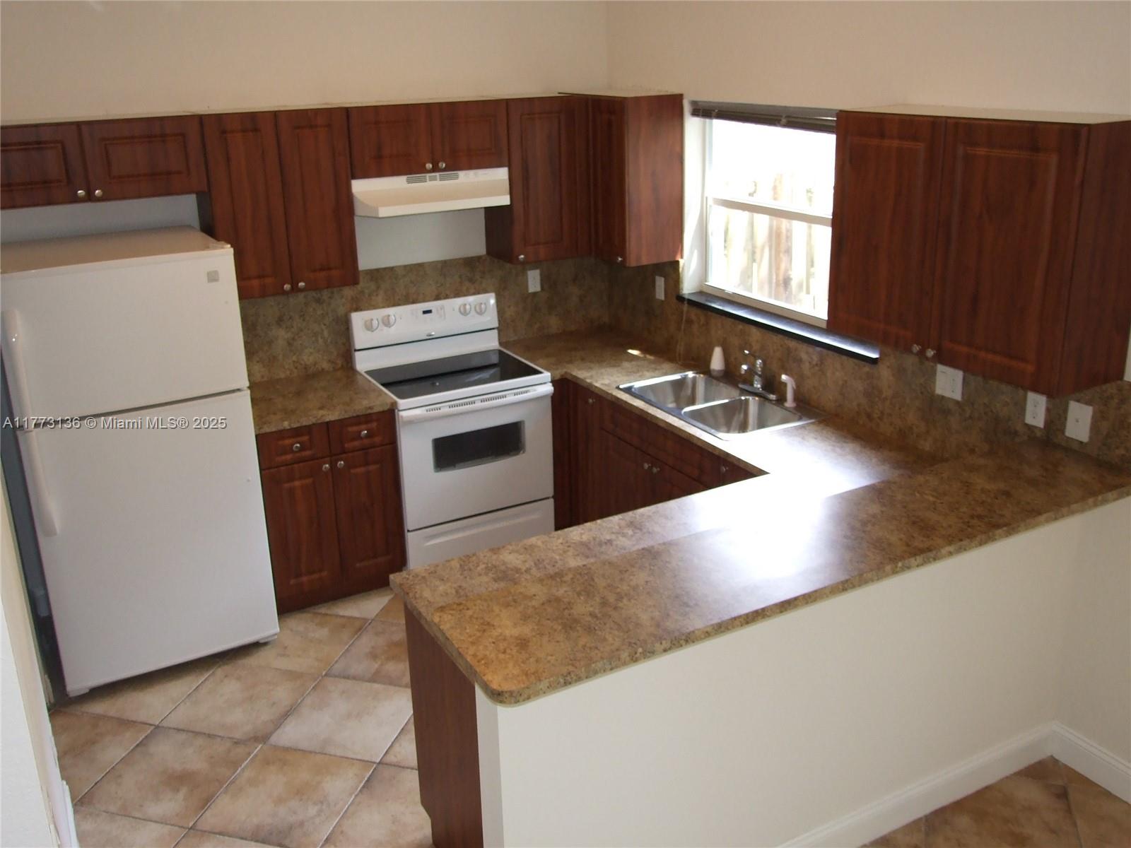 A kitchen features wood cabinets, laminate countertops, white appliances, and tiled flooring — 14082 SW 50th Ct, Miramar FL 33027, MIRAMAR, FL